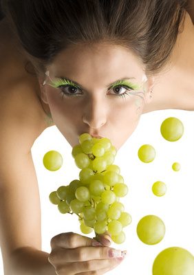 cute girl eating some green grape and looking in camera